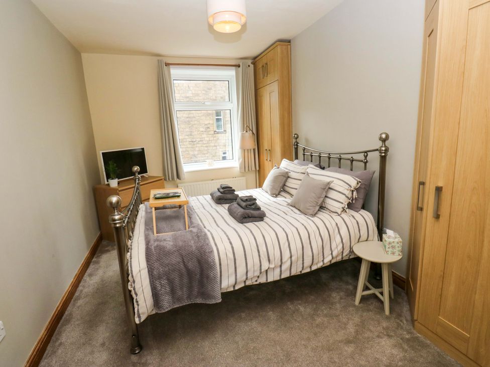 A bedroom with a bed and wardrobe at Steam View Cottage in Haworth