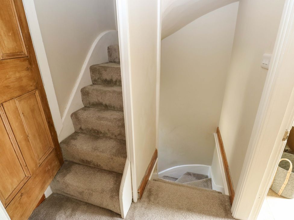 A staircase with carpet and a door at Steam View Cottage in Haworth