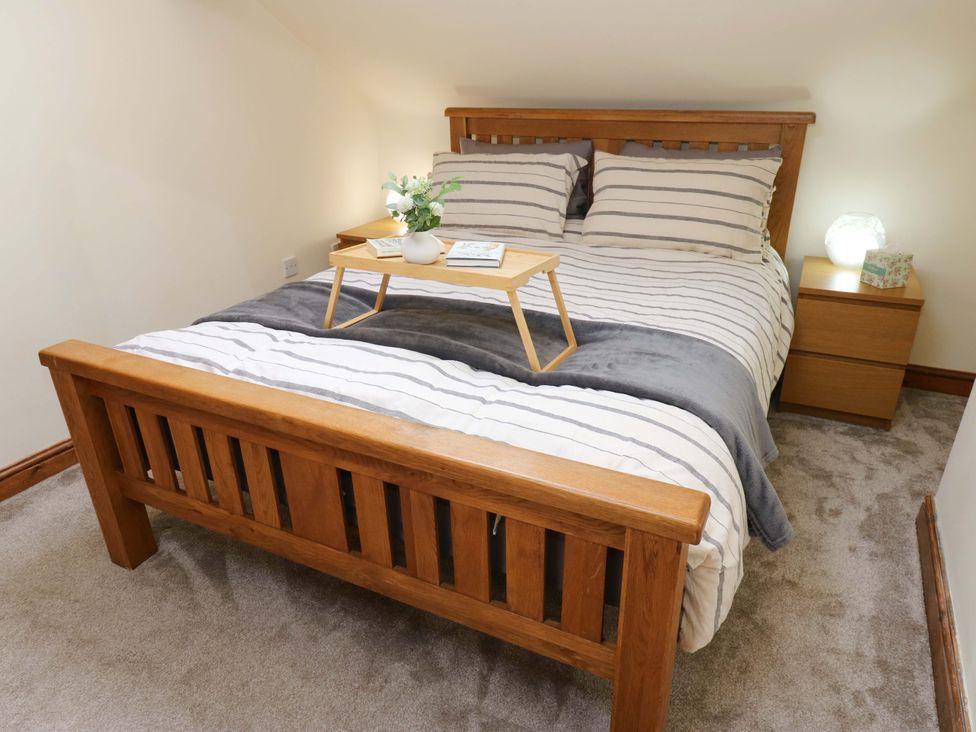 A bedroom with a bed and bedside table at Steam View Cottage in Haworth