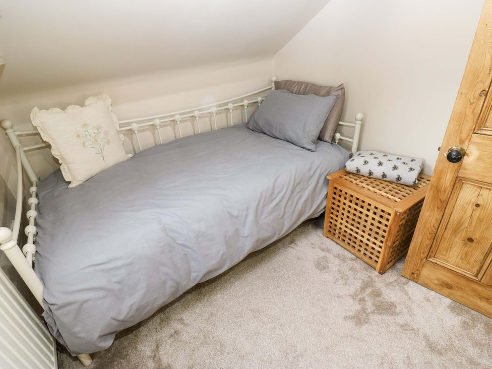 A bedroom with a bed and storage basket at Steam View Cottage in Haworth