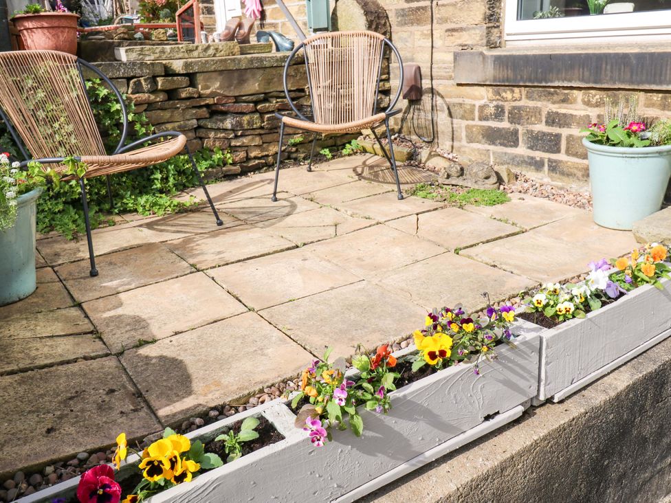 A garden with two chairs and flower pots at Steam View Cottage in Haworth