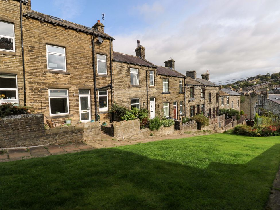 A row of houses with a grassy area in front at Steam View Cottage in Haworth