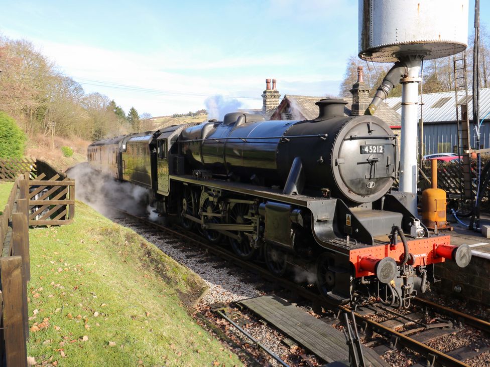 A steam locomotive and carriage at a railway station at Steam View Cottage in Haworth