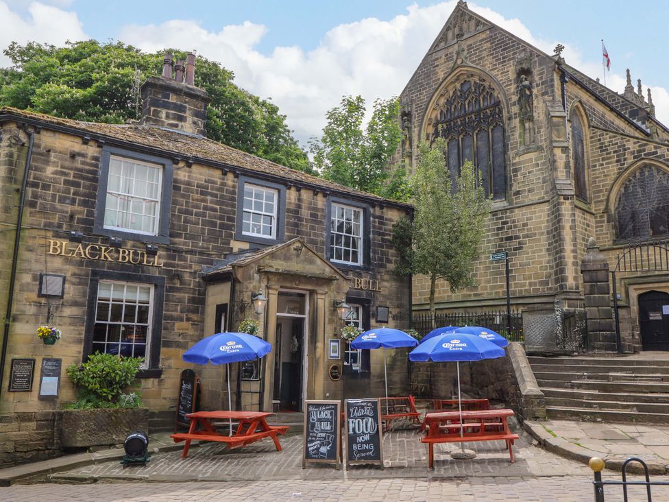 A pub with outdoor seating and a church nearby at Steam View Cottage in Haworth