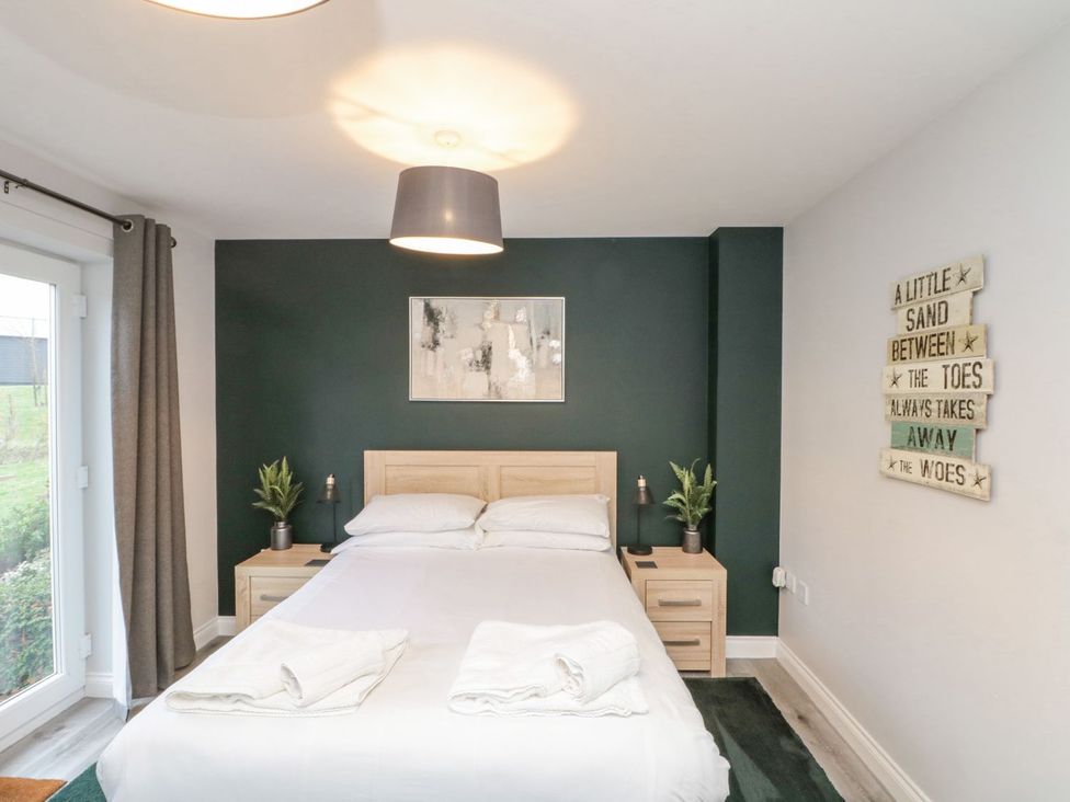 A bedroom with a bed and nightstands at Rosie's Retreat, Filey