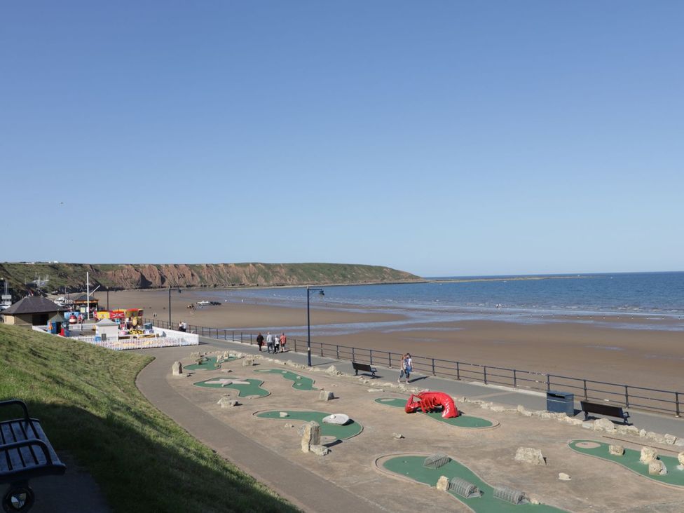 A beach with a mini-golf course and cliffs in the background at Rosie's Retreat in Filey