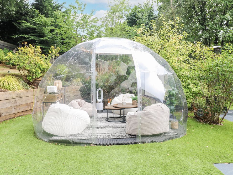 A transparent dome structure with seating and a table in the garden at Rockcliffe Grange in Mansfield