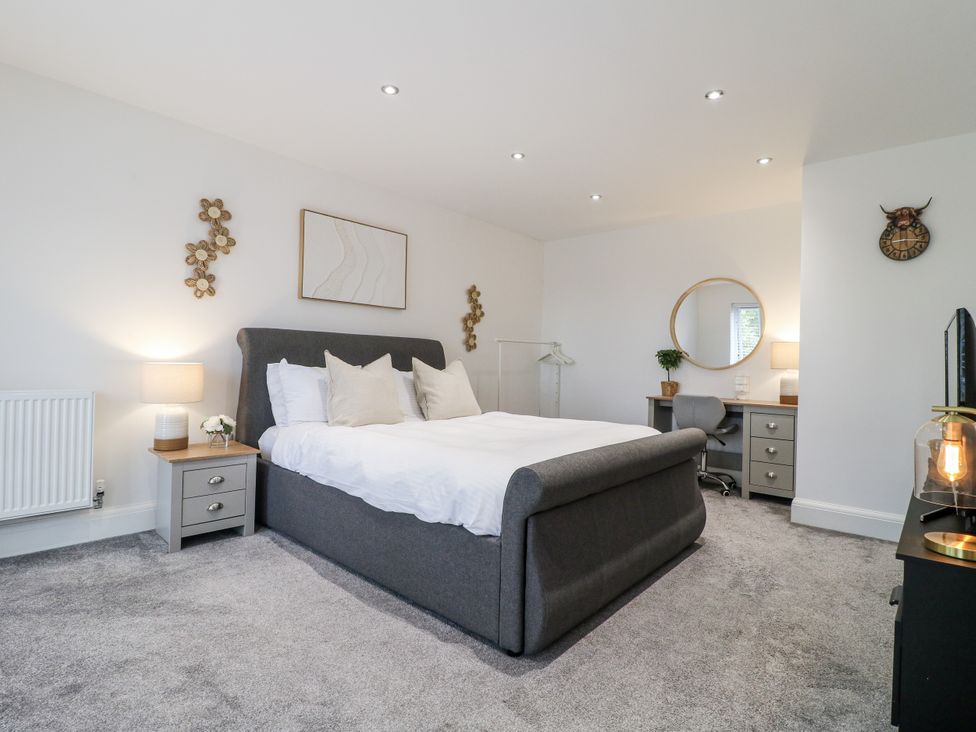 A bedroom with a bed, nightstand, lamp, desk, and mirror at Rockcliffe Grange in Mansfield