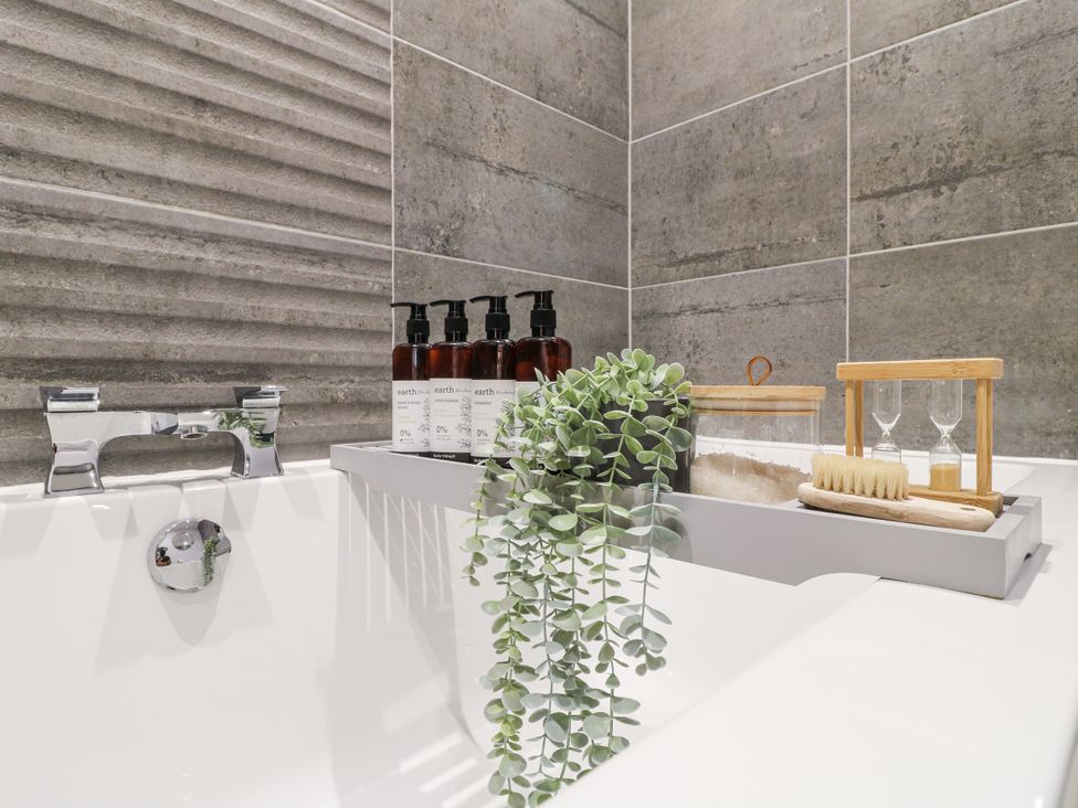 A bathtub with soap dispensers and a plant at Rockcliffe Grange in Mansfield