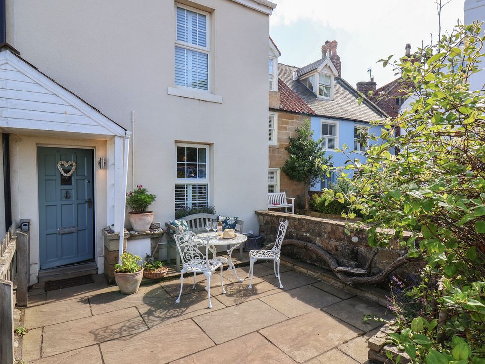 An outdoor seating area with a table and chairs at Woodbine Cottage Whitby