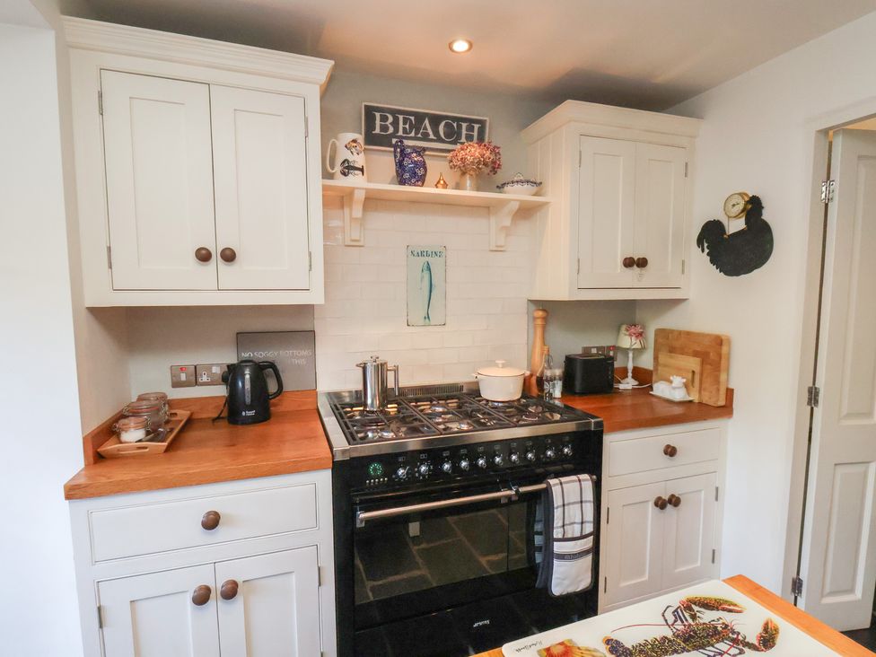 A kitchen with cabinets and a stove at Woodbine Cottage in Whitby