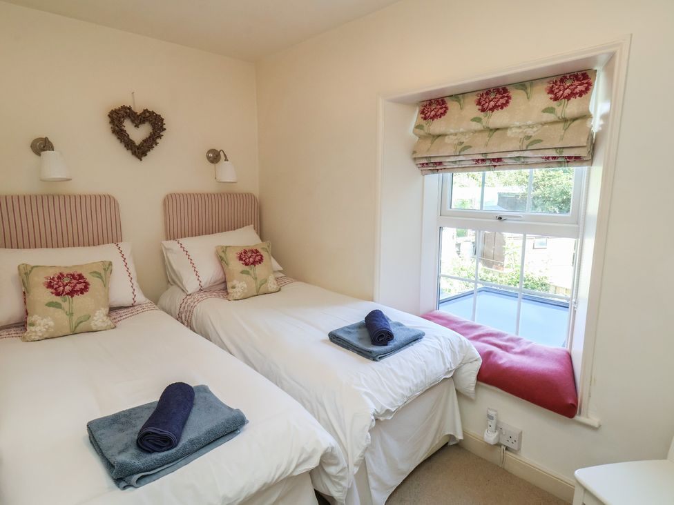 A bedroom with two beds and a window seat at Woodbine Cottage in Whitby
