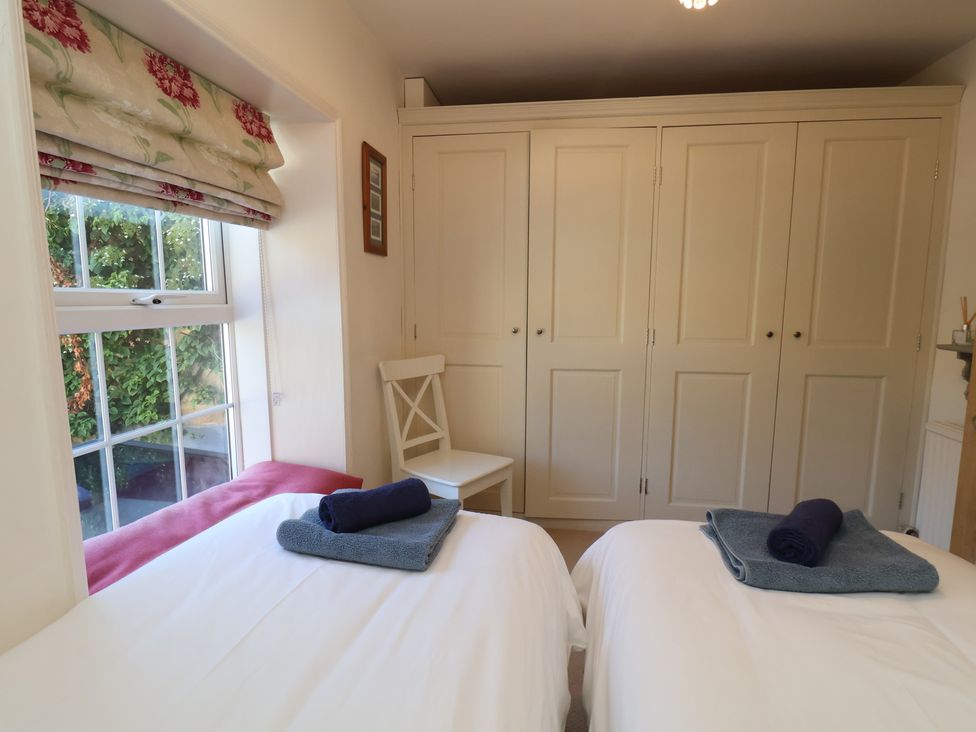 A bedroom with two beds and a wardrobe at Woodbine Cottage in Whitby
