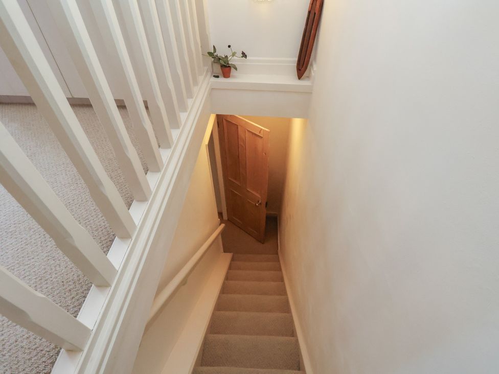 A staircase with a door at the bottom and a plant on the top at Woodbine Cottage in Whitby