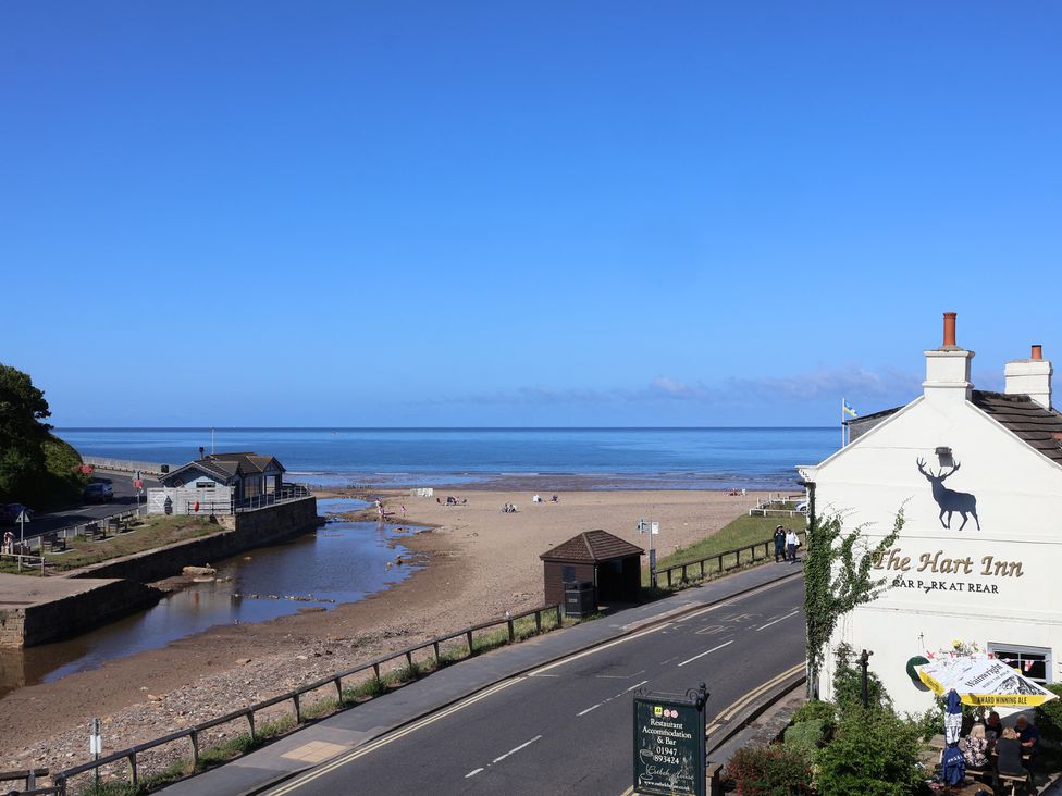 A beach view with The Hart Inn and sea at Woodbine Cottage in Whitby
