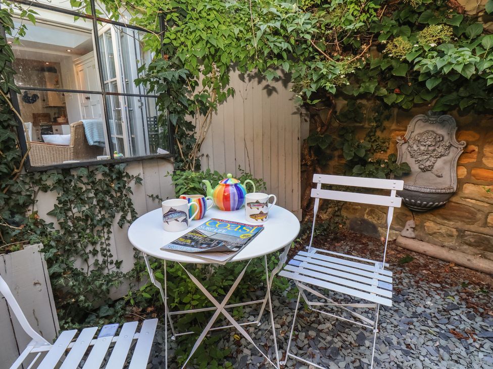 An outdoor seating area with a table and chairs at Woodbine Cottage in Whitby