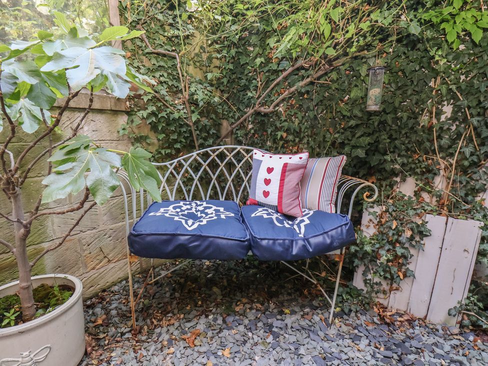 A garden with a bench and cushions at Woodbine Cottage in Whitby