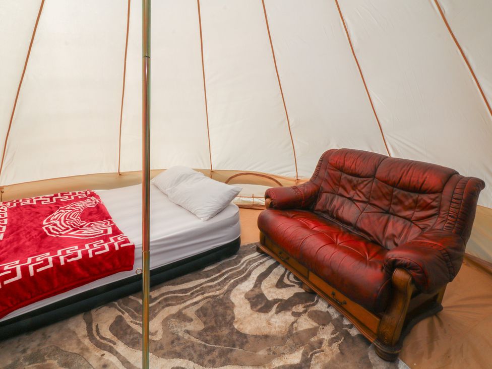 A tent with a bed and a couch at Bell Tent One