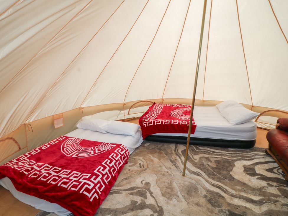 A tent with two beds and a rug at Bell Tent One