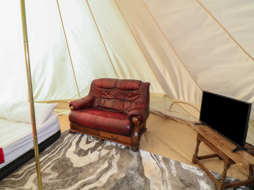 A seating area with a sofa and television at Bell Tent One in 