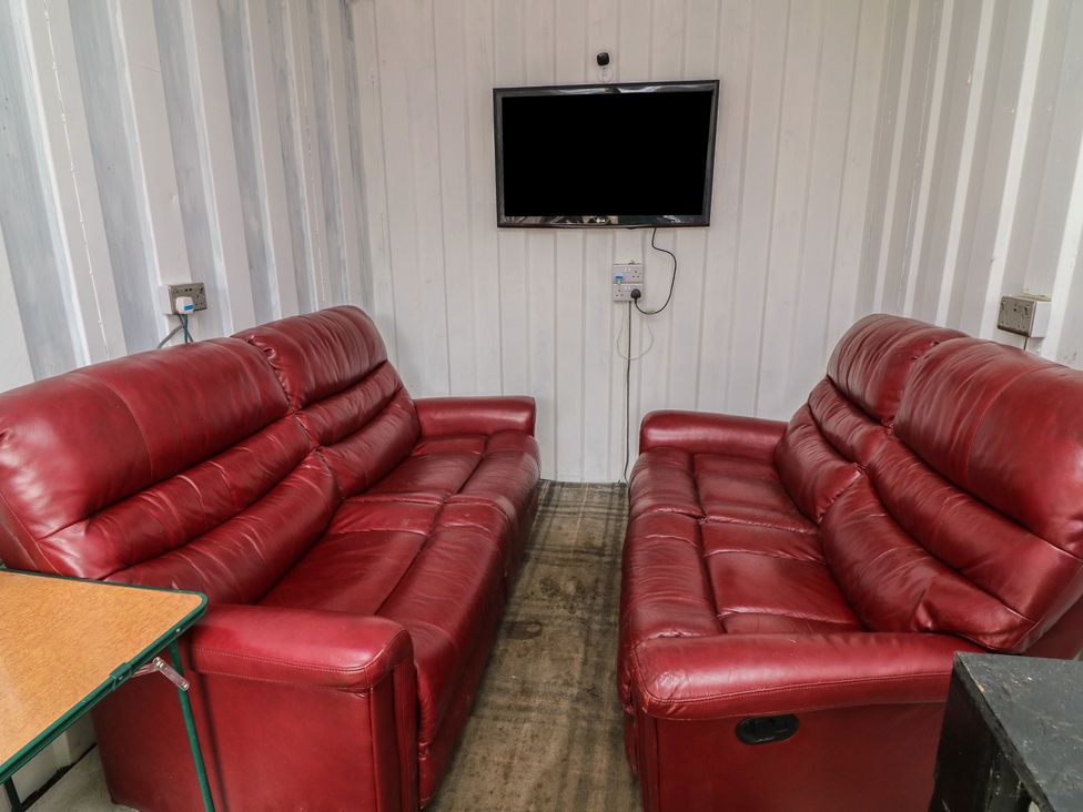A living room with two red sofas and a television at Bell Tent One