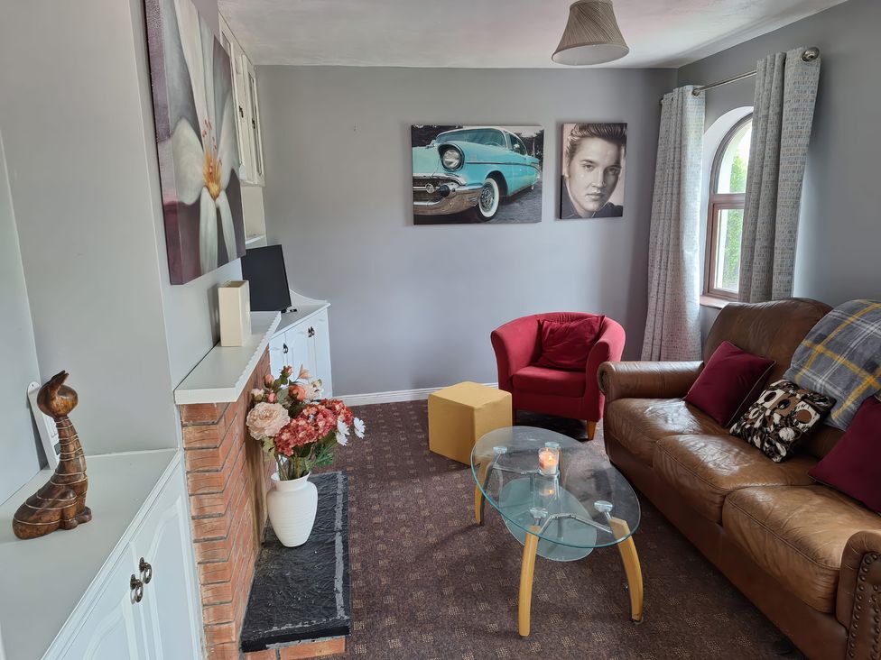 A living room with flower painting and a television at Lilly's Bungalow in Timoleague