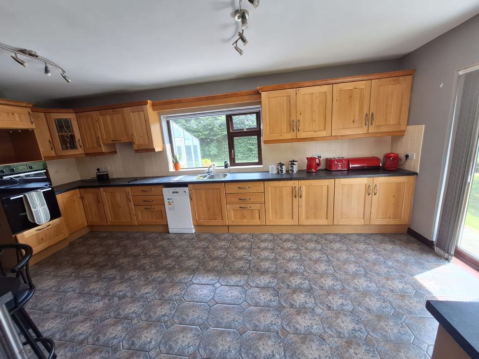 A kitchen with wooden cabinets and appliances at Lilly's Bungalow in Timoleague