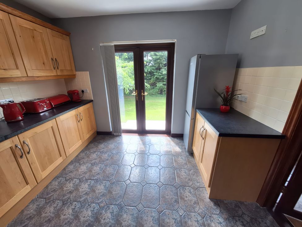 A kitchen with cabinets and a door leading outside at Lilly's Bungalow in Timoleague