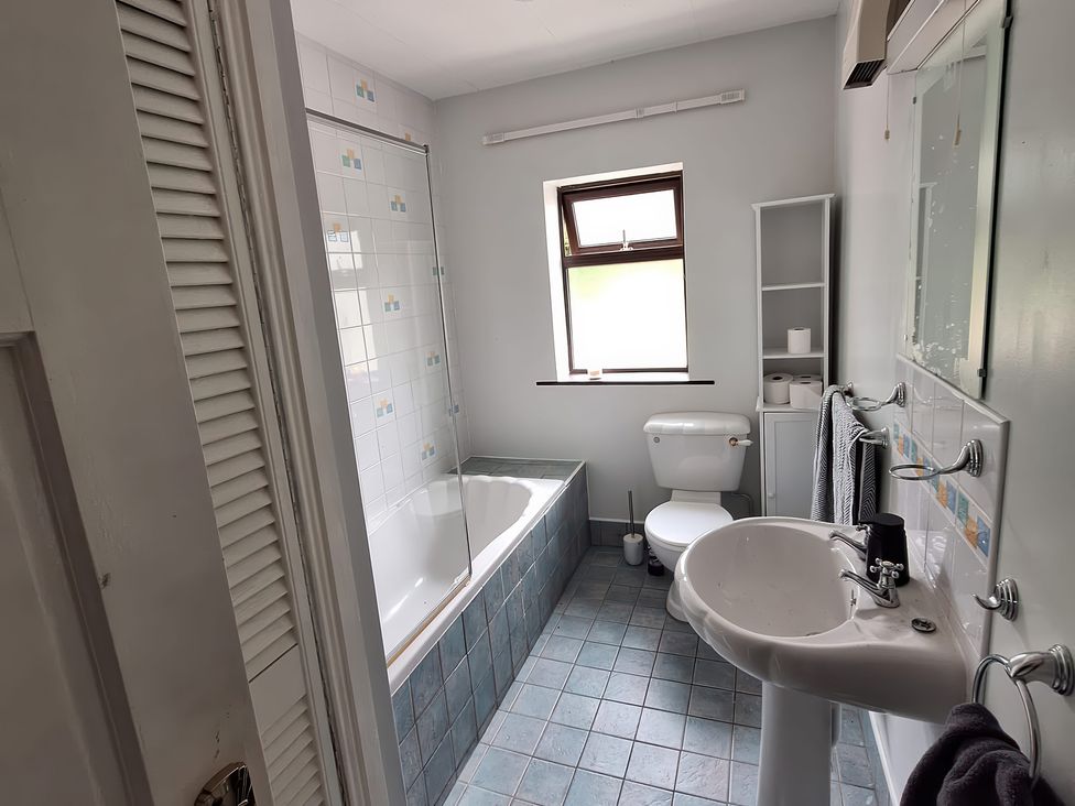 A bathroom with a bathtub, toilet and sink at Lilly's Bungalow, Timoleague