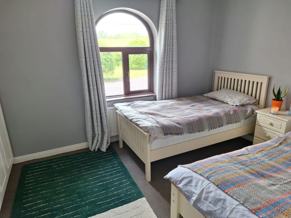 A bedroom with two beds and a window at Lilly's Bungalow in Timoleague