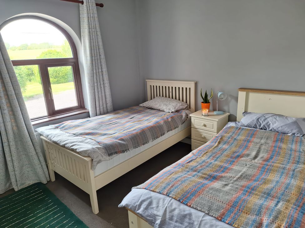 A bedroom with two beds and a nightstand at Lilly's Bungalow in Timoleague