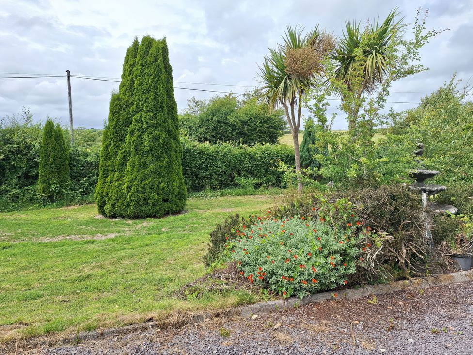 A garden with trees and a fountain at Lilly's Bungalow in Timoleague