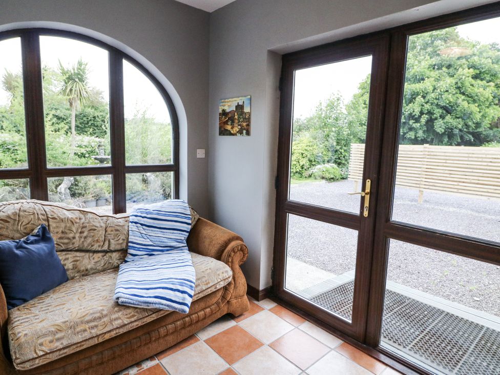 A conservatory with a sofa and window at Lilly's Bungalow in Clonakilty, County Cork