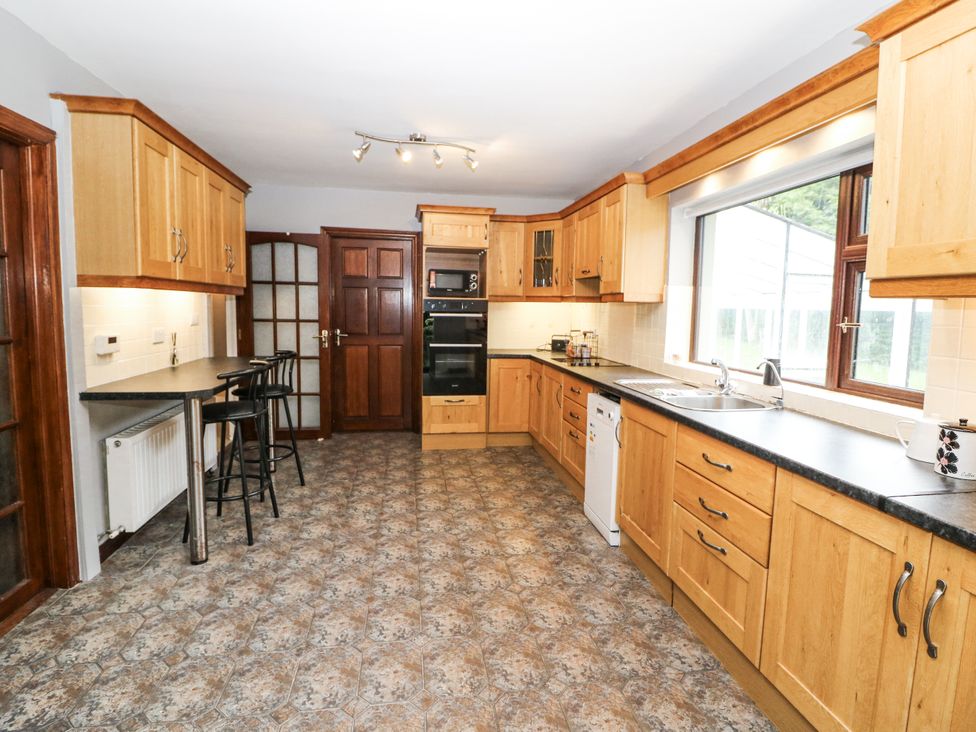 A kitchen with wooden cabinets and appliances at Lilly's Bungalow in Clonakilty, County Cork