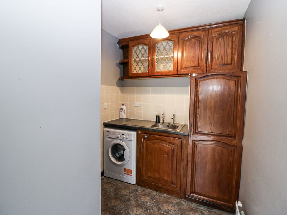 A kitchen with cupboards and a washing machine at Lilly's Bungalow, Clonakilty, County Cork