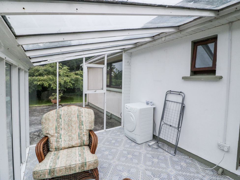 A conservatory with a chair and washing machine at Lilly's Bungalow in Clonakilty, County Cork