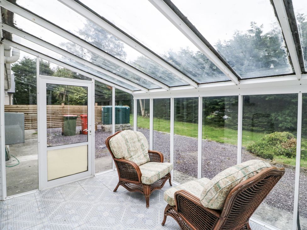 A conservatory with wicker chairs and garden view at Lilly's Bungalow Clonakilty, County Cork