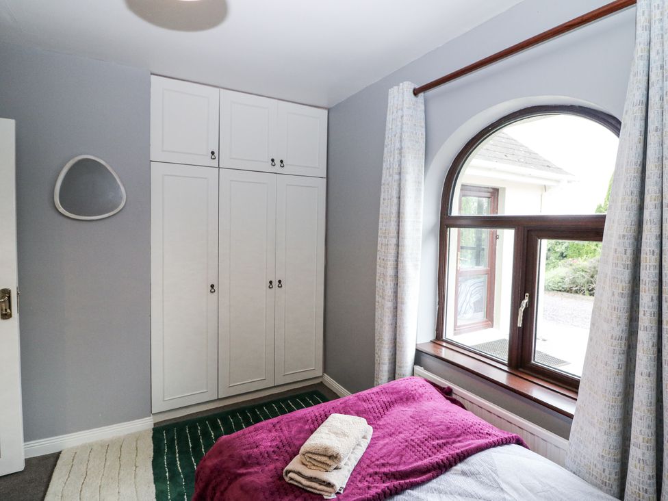 A bedroom with a wardrobe and window at Lilly's Bungalow in Clonakilty, County Cork