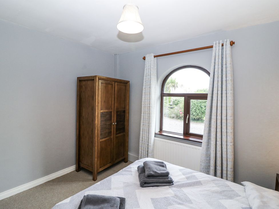 A bedroom with a bed and wardrobe at Lilly's Bungalow in Clonakilty, County Cork