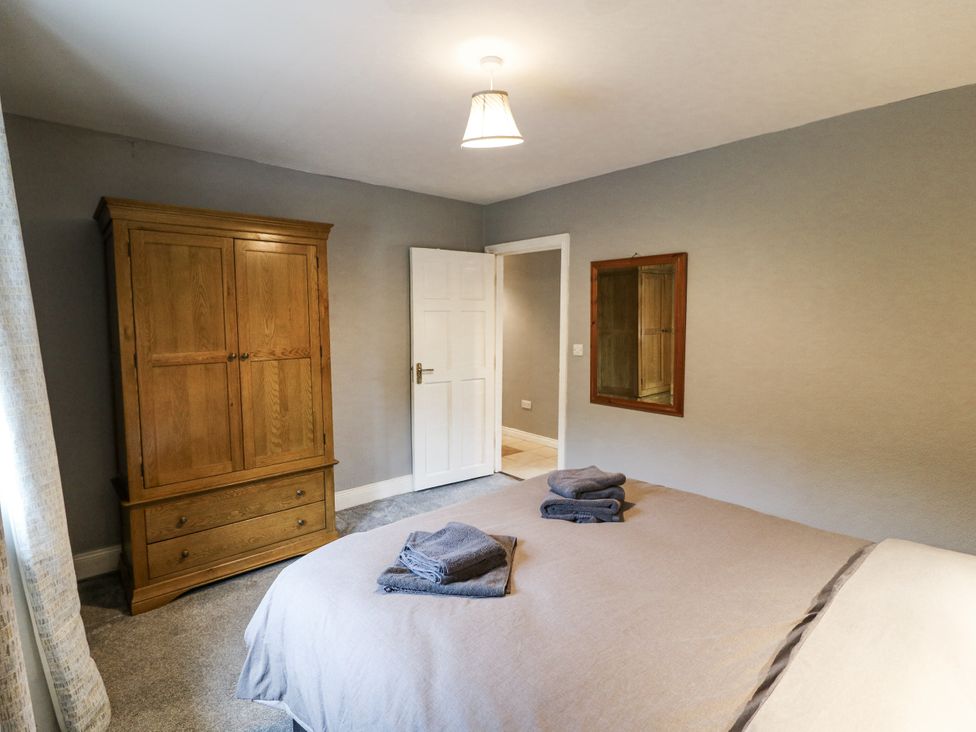 A bedroom with a wooden wardrobe and a bed with towels at Lilly's Bungalow in Clonakilty, County Cork