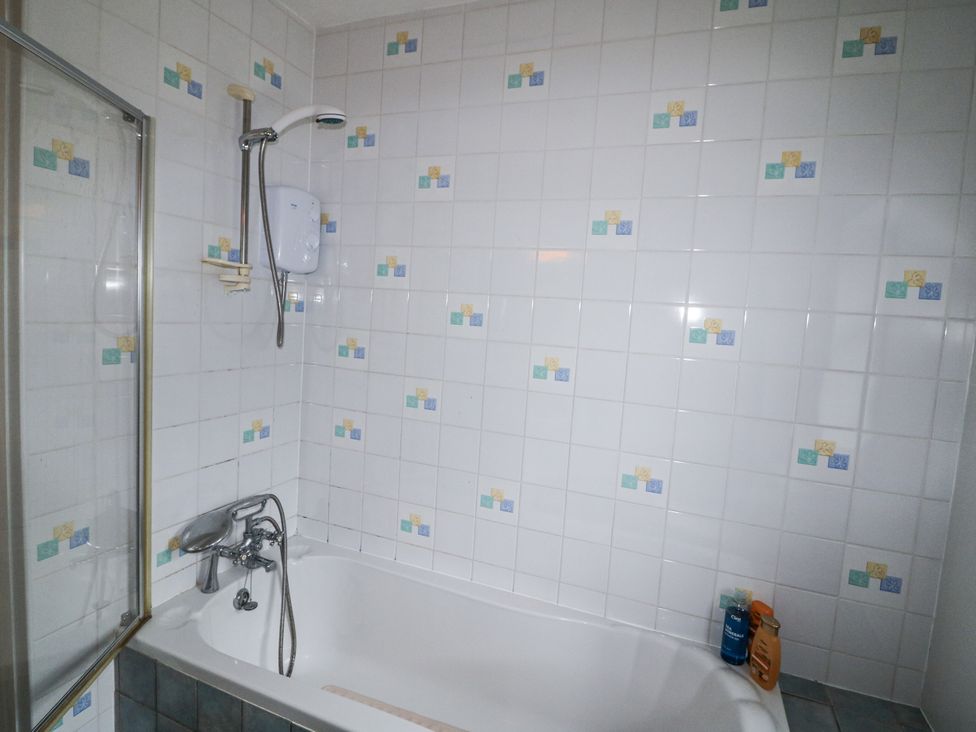 A bathroom with a shower above the bathtub at Lilly's Bungalow in Clonakilty, County Cork