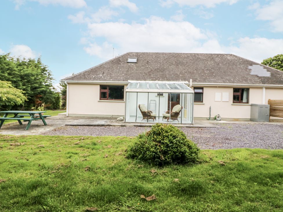 A bungalow with a conservatory and seating area in the garden at Lilly's Bungalow Clonakilty, County Cork