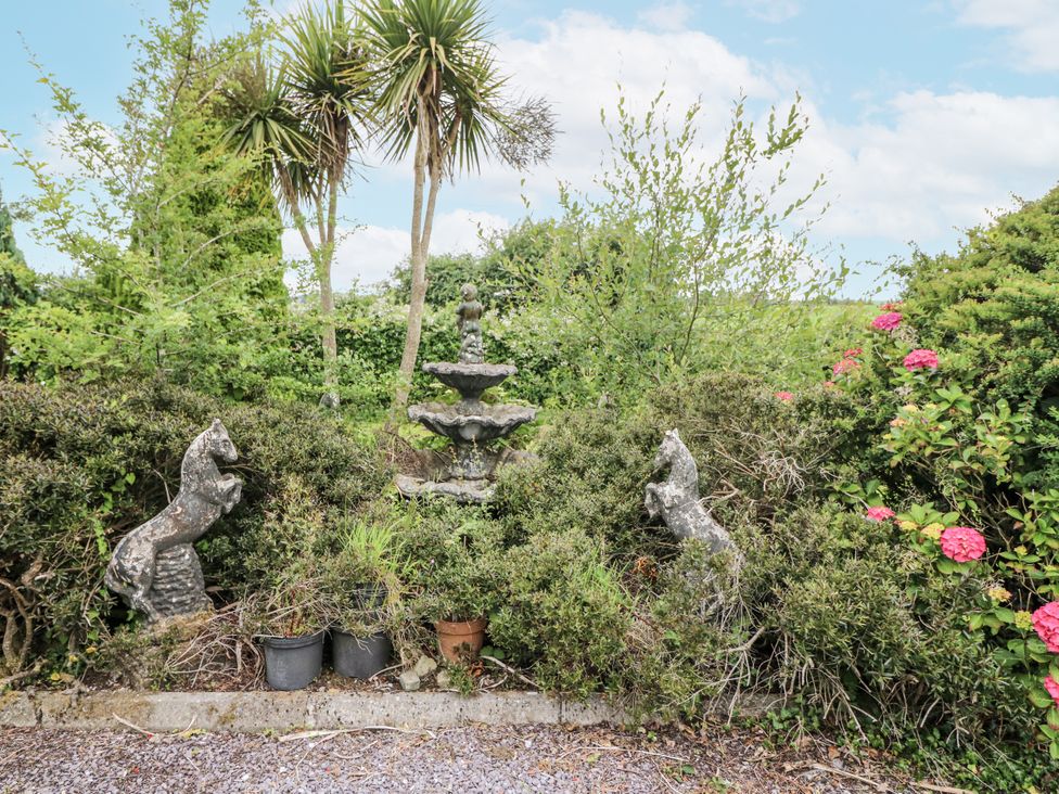 A garden with a fountain and stone statues at Lilly's Bungalow Clonakilty County Cork