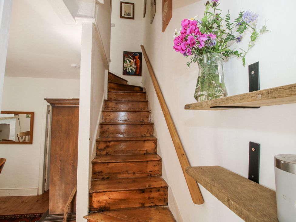 A staircase with a wooden handrail and a flower vase at 157 Watling Street South Church Stretton