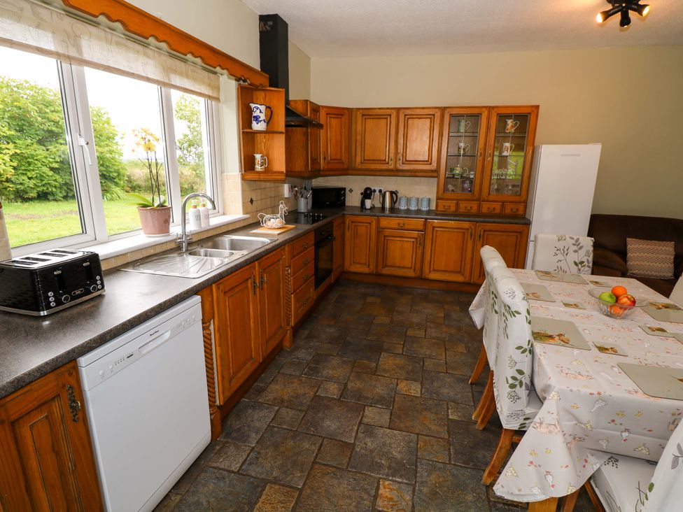 A kitchen with wooden cabinets and a dining table at CARROWREAGH