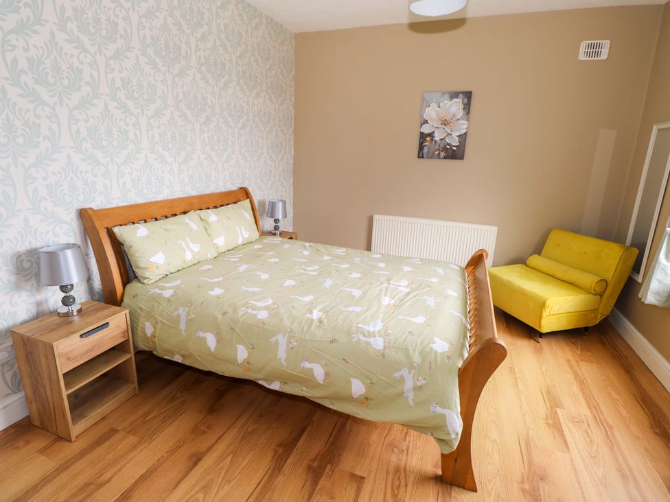 A bedroom with a bed, bedside table, lamp, and armchair at CARROWREAGH