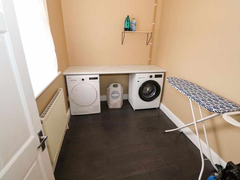 A laundry room with a washing machine, tumble dryer, and ironing board at CARROWREAGH