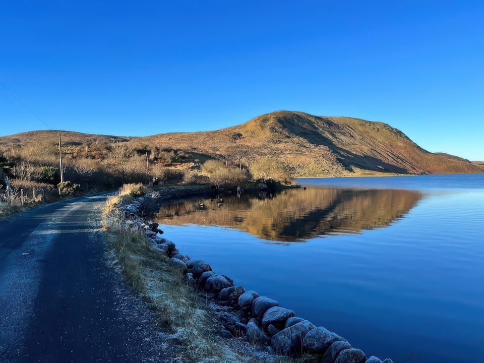 A road beside a lake with a mountain in the background at Carrowreagh, Aclare, County Sligo