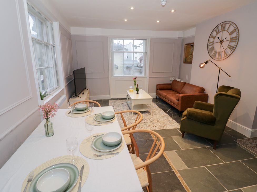 A living room with a sofa and dining area at 12 Montpellier Arcade in Cheltenham