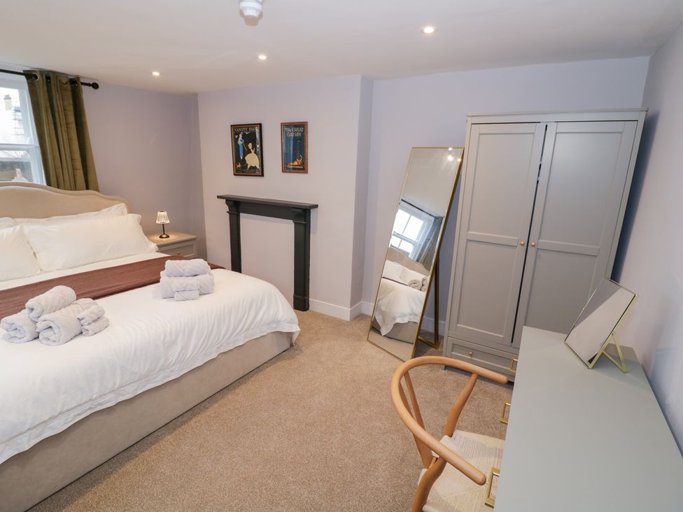 A bedroom with a bed, wardrobe, mirror, and desk at 12 Montpellier Arcade Cheltenham